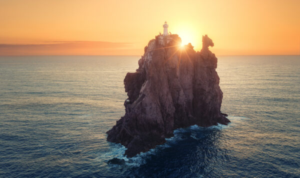 ..the sun relieves the lighthouse from its night watch, casting a golden morning glow.